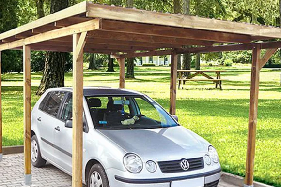 Ein silbernes Auto unter einem neuen Carport aus Holz.